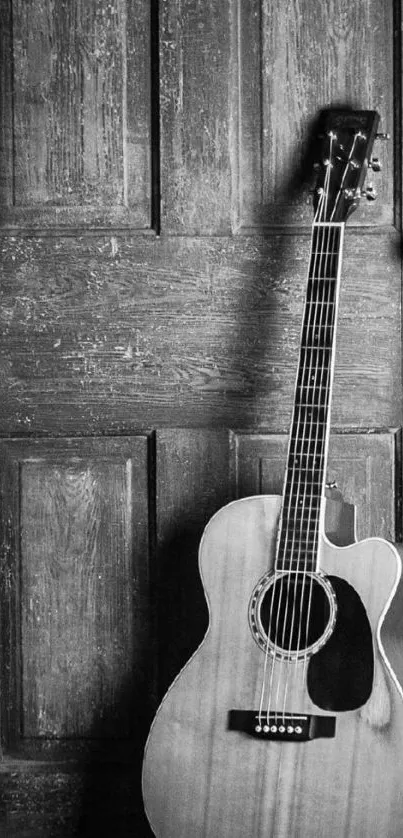 Rustic acoustic guitar leaning against a wooden door.