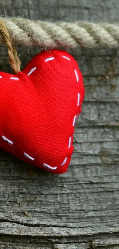 Red heart on rustic rope against wooden backdrop.