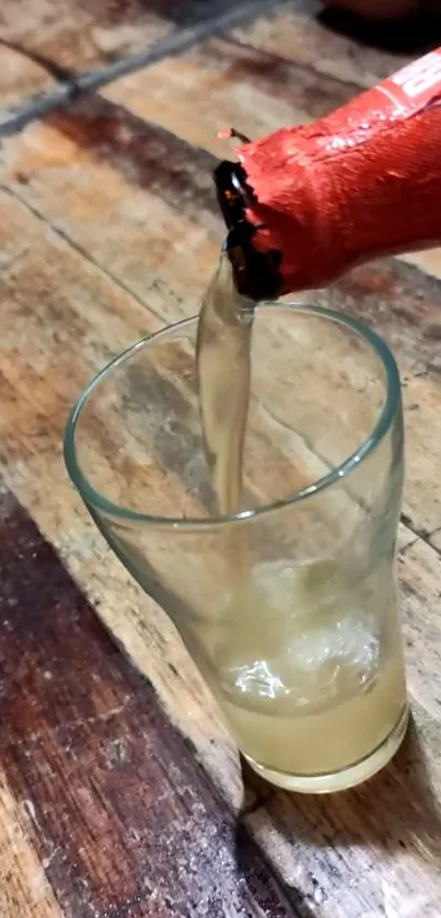 Drink pouring into a glass on a wooden table.