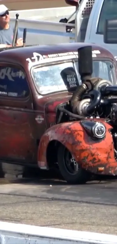 Rustic red hotrod with exposed engine parked on a sunny day.