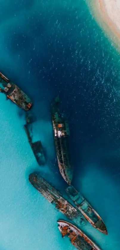 Aerial view of shipwrecks in vibrant blue ocean with sandy shoreline.