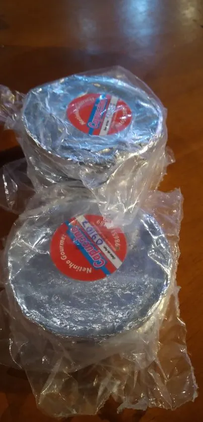 Silver objects wrapped in plastic on a wooden surface.