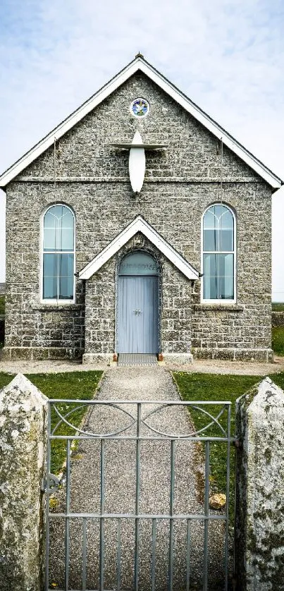 Rustic stone church in countryside with gated pathway.