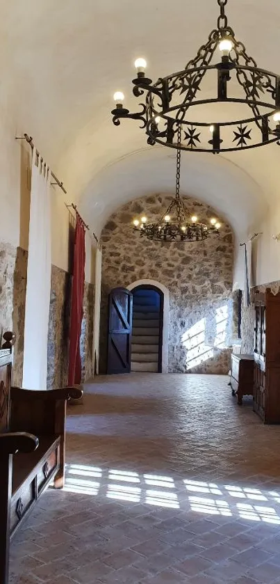 Rustic stone hallway with chandeliers and antique furniture in natural light.