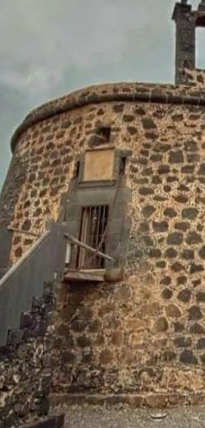 Rustic stone tower with intricate architecture against cloudy sky.