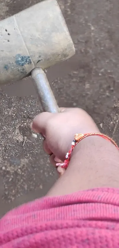 Hand gripping a rustic hammer over earthy ground background