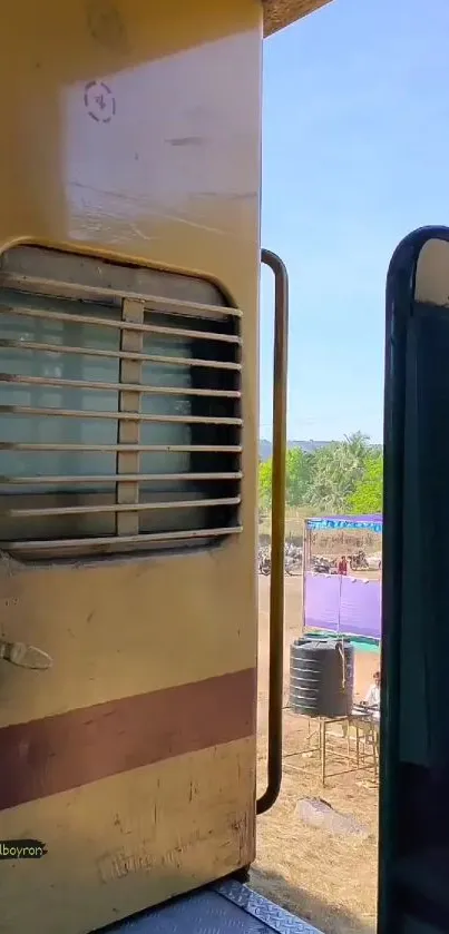 View through a rustic train door with vibrant blue sky.