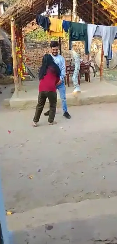 People interacting in a rustic village backyard with laundry hanging.