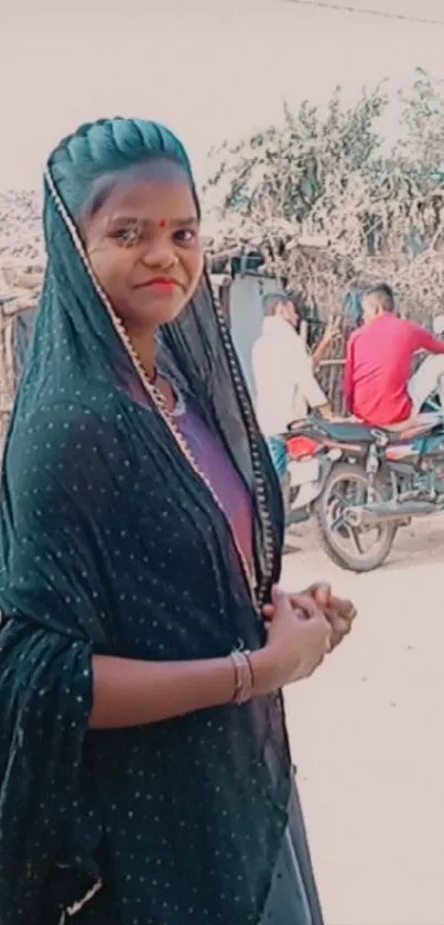 Woman in traditional attire in a rural village setting with rustic background.