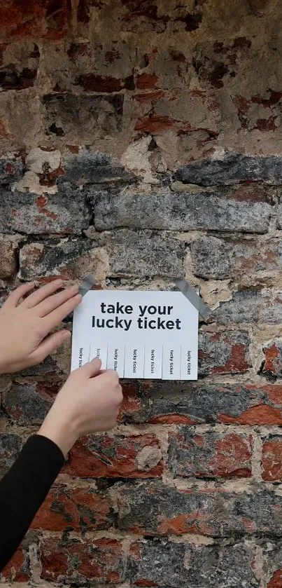 Hands peeling lucky ticket from rustic brick wall with textured design.