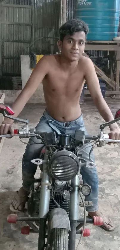 Young rider on a vintage motorcycle in a rustic workshop setting.