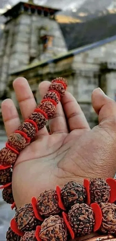 Hand holding sacred beads before temple.