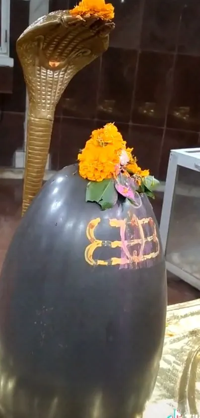 Sacred Shivling decorated with orange flowers and a golden background.