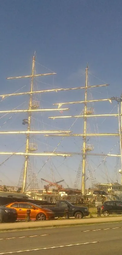 Majestic sailboat docked at city harbor under clear blue sky.