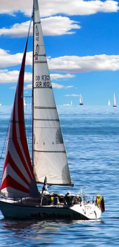 Sailboat on a calm ocean under a blue sky with clouds.