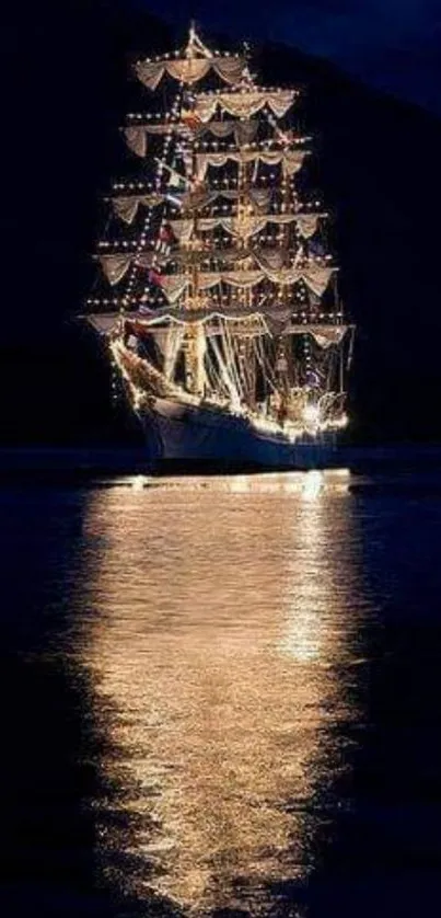 Illuminated sailing ship with water reflection at night.