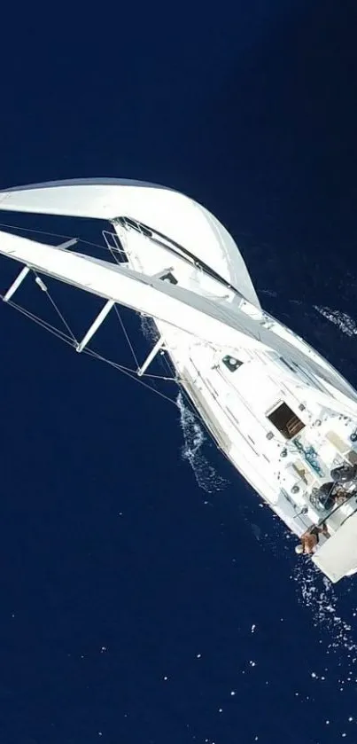 Aerial view of a sailing yacht on dark blue ocean waters.