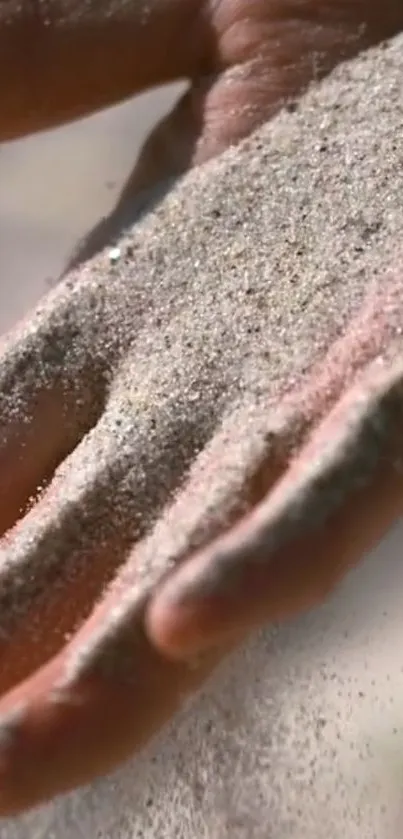 Close-up of sand flowing over a hand, creating a serene and natural wallpaper.