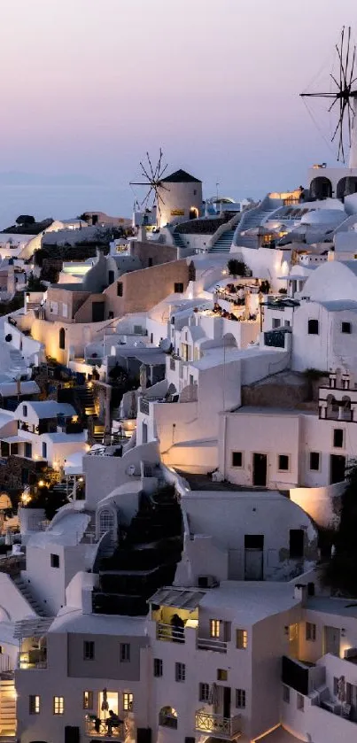 Evening view of Santorini's iconic white buildings and windmills at sunset.