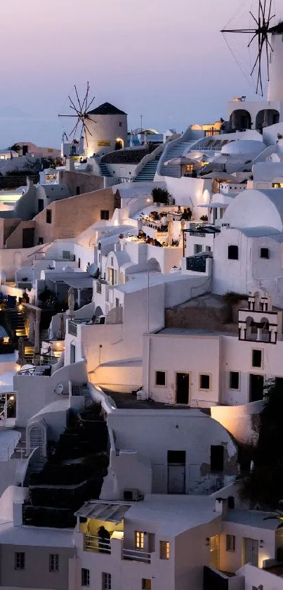 A beautiful sunset view of Santorini with white buildings and windmills.