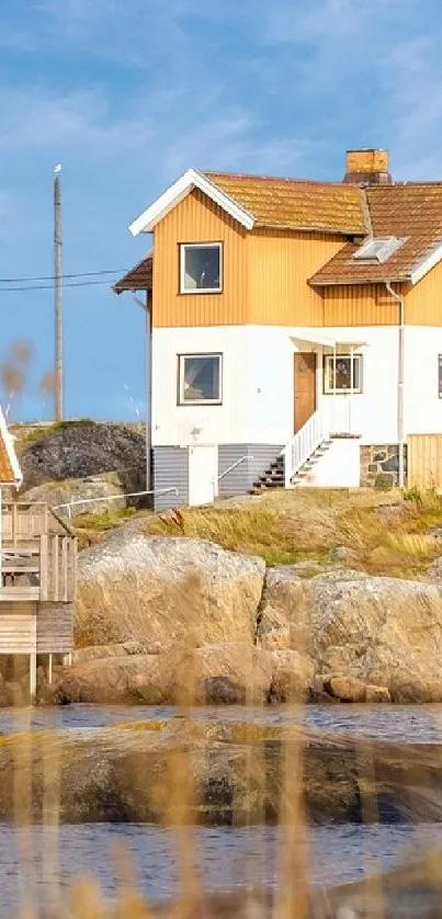 Scandinavian coastal house on rocky shore with blue sky.