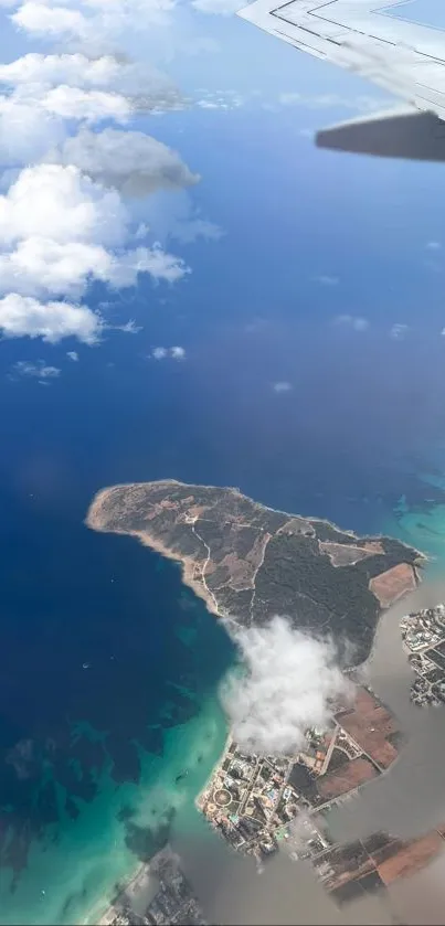 Aerial island view with blue ocean and clouds from an airplane window.