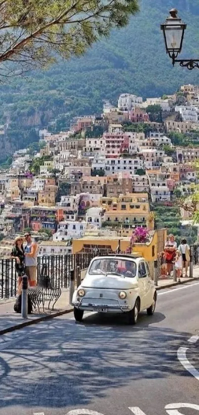 Vintage car on scenic Amalfi Coast road with colorful hillside houses.