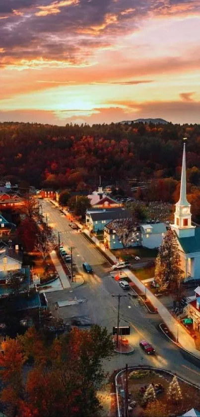 Aerial view of a town with autumn foliage and sunset sky backdrop.