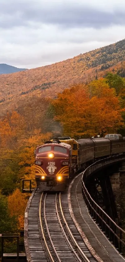 Train on a track surrounded by autumn foliage in a mountain setting.