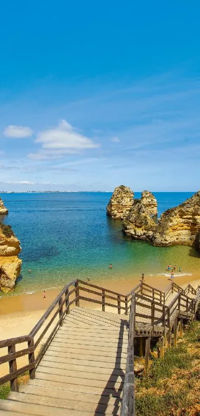 Wooden stairs leading to picturesque beach with blue sky and cliffs.