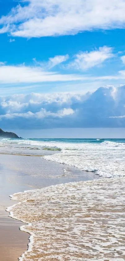 Scenic coastal view with blue sky and ocean waves on a sandy beach.