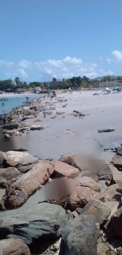 Beautiful beach with rocks leading to the ocean under a clear blue sky.