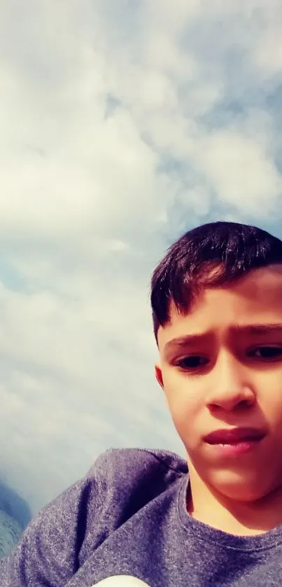 Boy takes a selfie at a cloudy beach with blue sky.