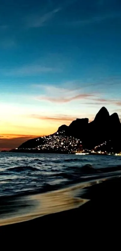 Sunset over beach with ocean and silhouetted mountains.