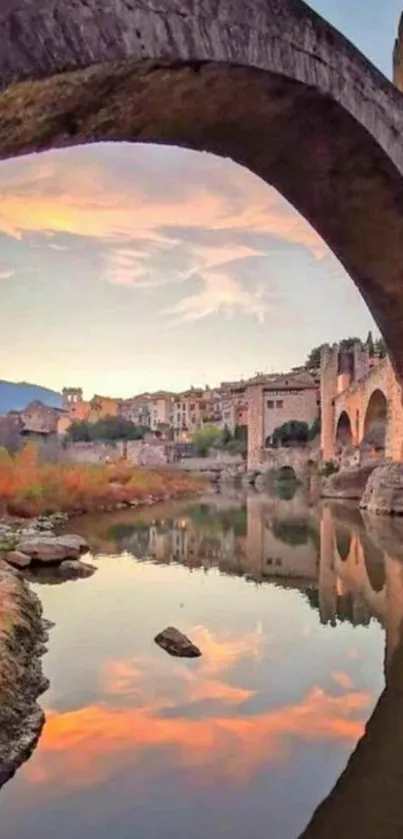 Beautiful reflection of a stone bridge over a calm river with sunset sky.