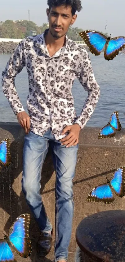 Man in floral shirt with blue butterflies at a waterfront.