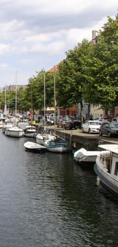 Serene canal with boats and trees on mobile wallpaper.