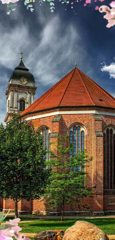 Charming church with red roof, surrounded by greenery and flowers against a blue sky.