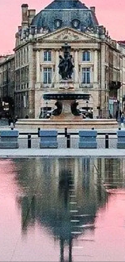 Elegant city building reflected in calm pink-hued waters at dawn.