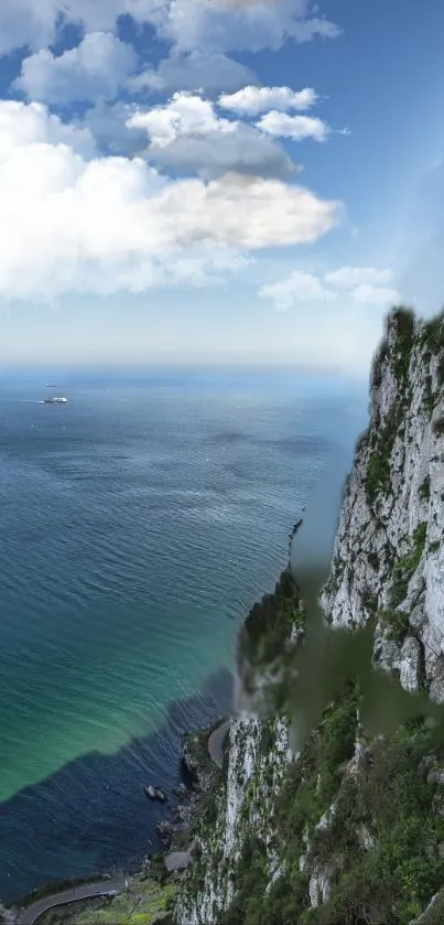 Majestic cliff over a vast blue ocean under a clear sky with white clouds.