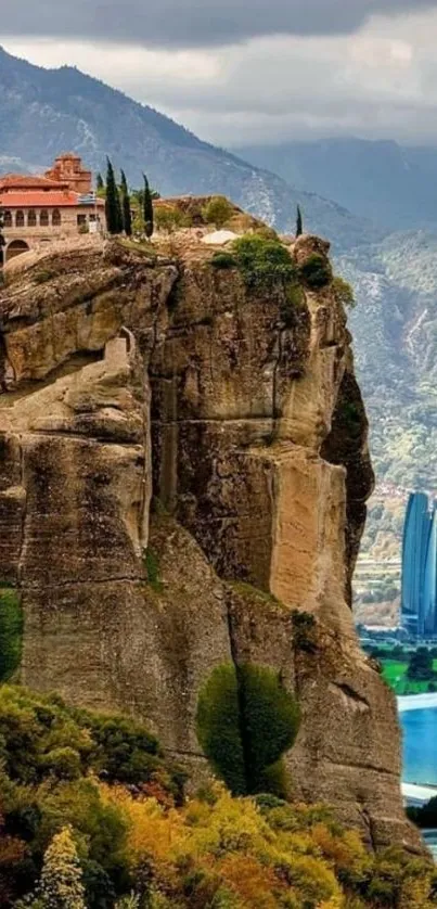 Breathtaking cliffside view with house, greenery, mountains, and lake.