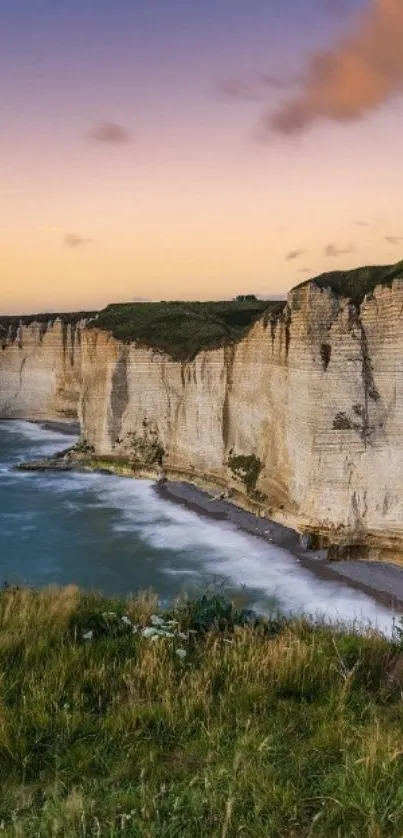 Breathtaking coastal cliffs at sunset with ocean waves and grassy foreground.