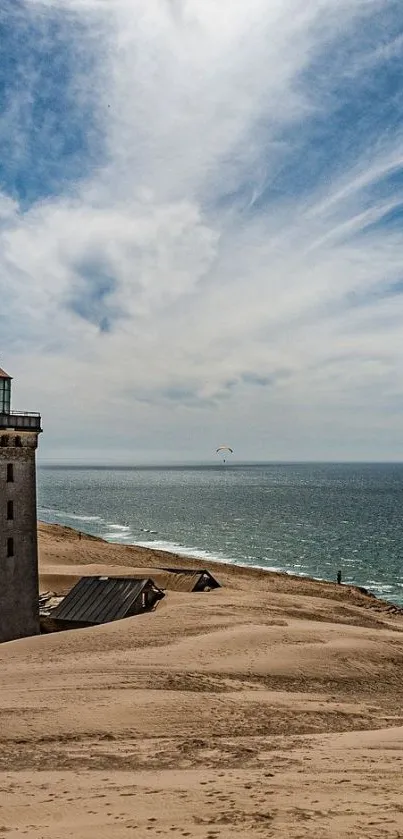 Lighthouse on sandy coast with blue sky.