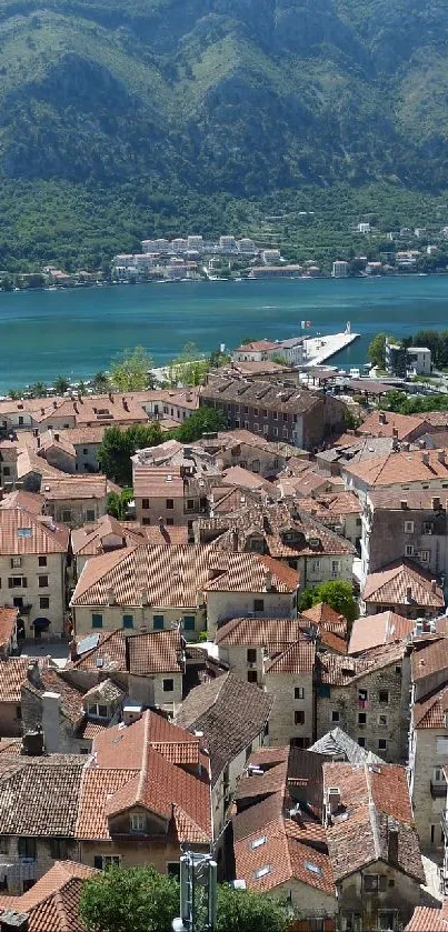 Aerial view of a coastal town with terracotta rooftops surrounded by blue bay and mountains.