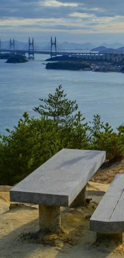 Scenic coastal bench overlooking ocean and bridge, under a blue sky.