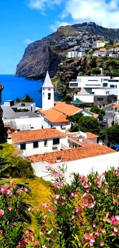 A scenic view of a Mediterranean village by the sea with vibrant flowers and cliffs.