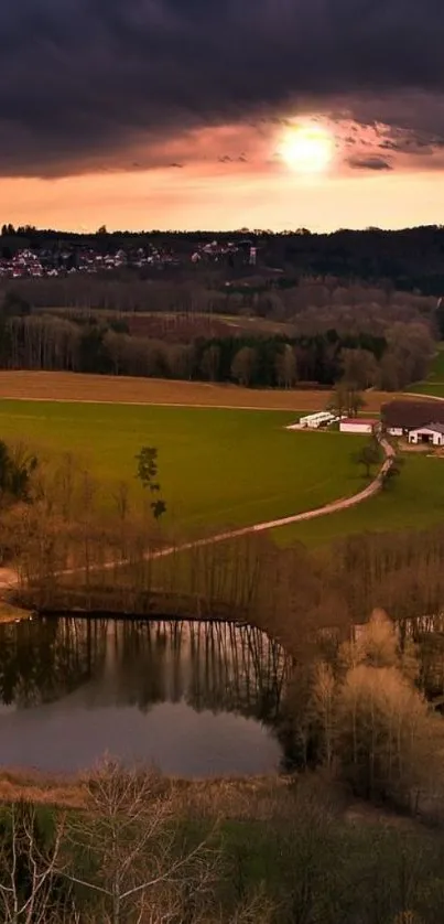 Scenic sunset over countryside with lake and fields.