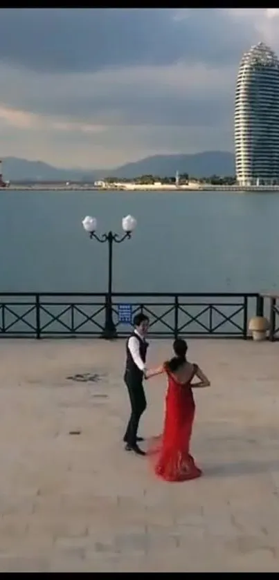 Couple dancing by waterfront with modern towers.