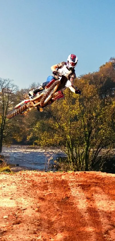 Dirt bike jumping through scenic autumn landscape.