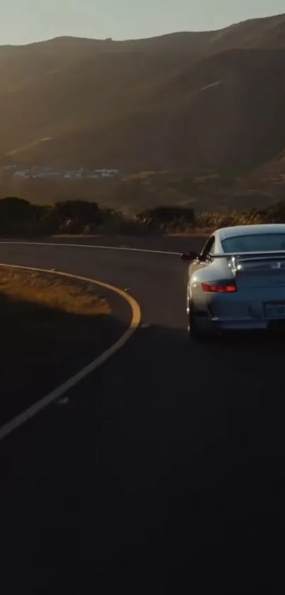 Sports car on a winding road at sunset, captured in a scenic mobile wallpaper.